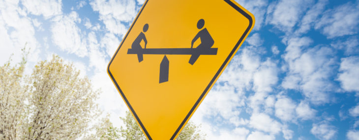 Teeter-totter yellow sign on sky background